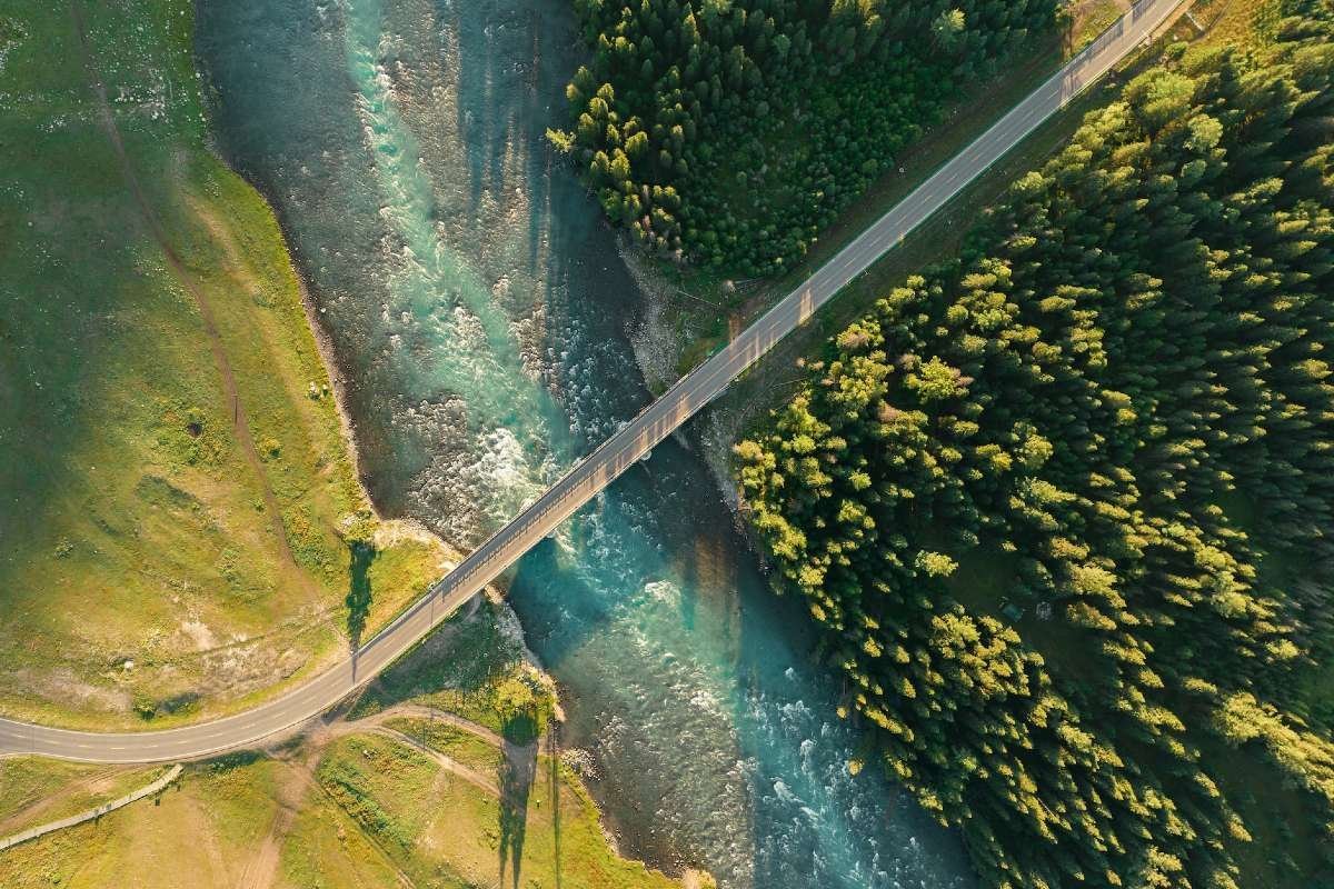 Scenic drone shot of a highway bridge over a mountain river in a lush forest landscape