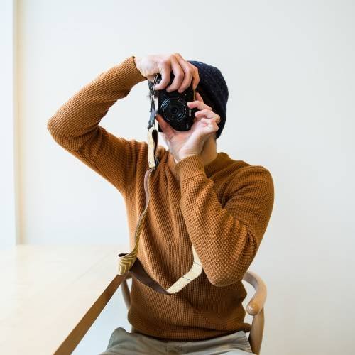 A man wearing brown sweatshirt holding camera